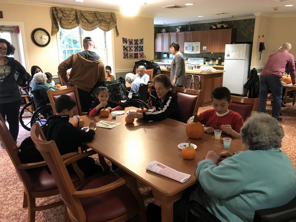 Cub Scout Pack 223 members paint pumpkins with residents of The Chelsea at East Brunswick